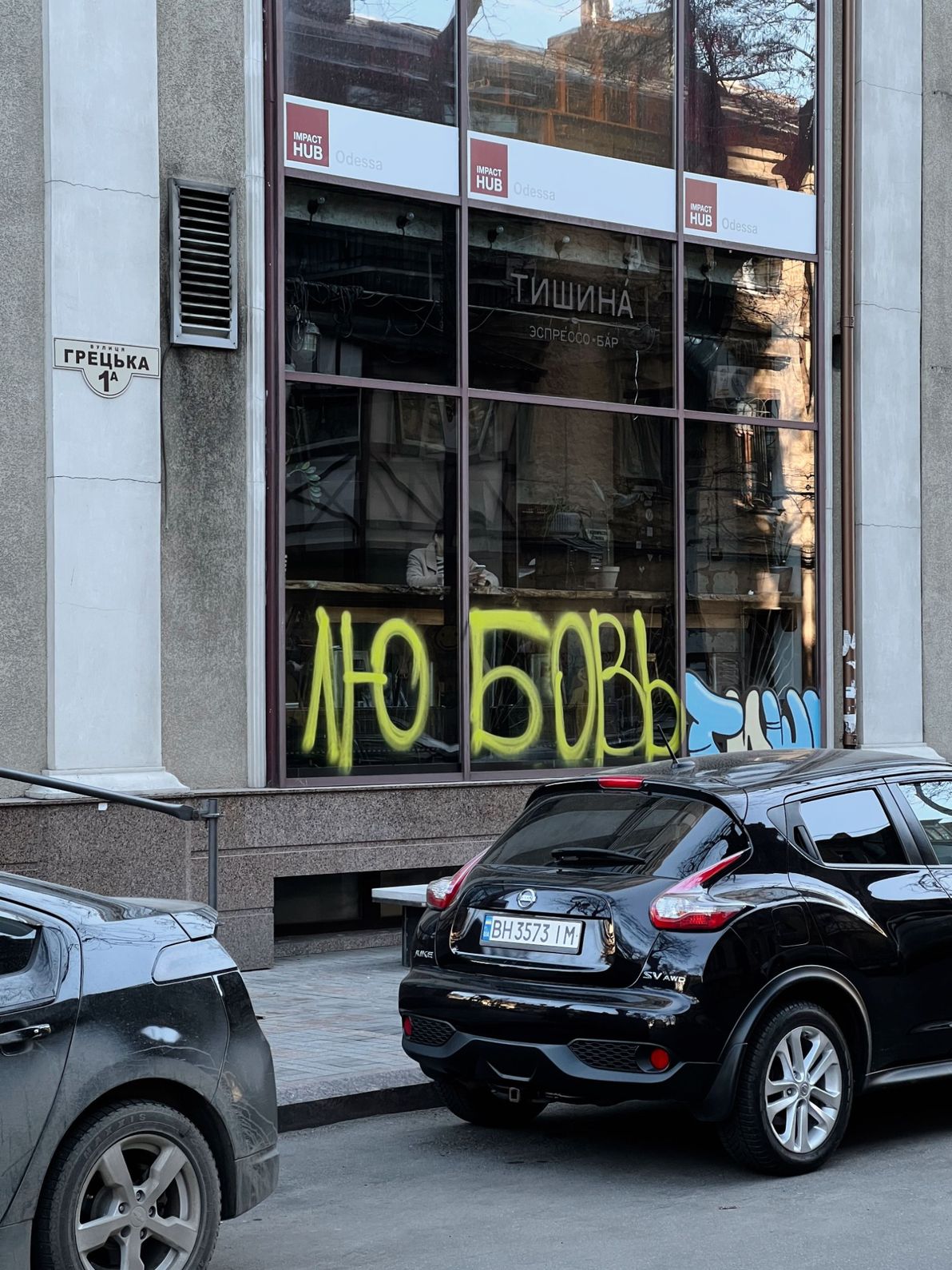 parked cars beside a modern building with graffiti on the window